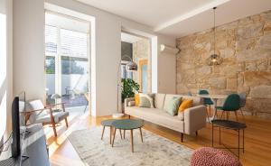sala de estar con sofá y pared de piedra en Trindade Premium Suites & Apartments en Oporto