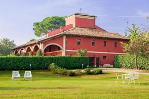 un edificio rojo con sillas blancas delante en Cà Palazzo Malvasia - BolognaRooms en Sasso Marconi