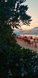 a group of people sitting on benches on the beach at Dimitra Apartments K in Kommeno