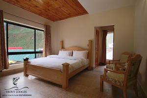 a bedroom with a bed and a large window at Trout Lodges in Ghumla