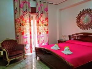 a bedroom with a pink bed and a chair at 24 Cannoli in Leonforte