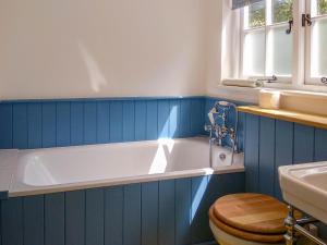 a blue bathroom with a tub and a toilet at 7 Whinlands in Thorpeness +7 photos