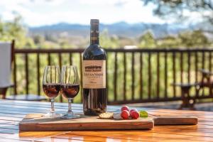 una bottiglia di vino e due bicchieri su un tavolo di legno di Riverside Guest Lodge a Oudtshoorn