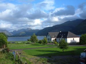 a house in a field next to a body of water at Highland Croft B&B in Onich