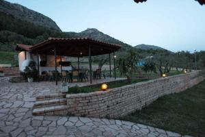 un patio con una pared de piedra y un pabellón en Almini Apartments, en Plataria