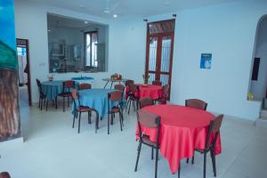 uma sala de jantar com mesas e cadeiras com capas vermelhas e azuis em The Cappuccino Hotel em Negombo