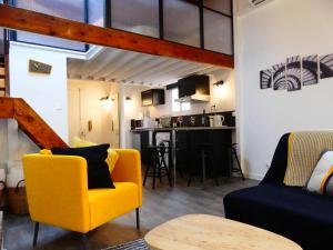 uma sala de estar com uma cadeira amarela e uma cozinha em Les Bernardines em Aix-en-Provence