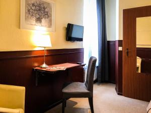 um quarto com uma secretária com uma cadeira e uma televisão em Hotel Hanseatic em Lübeck