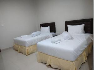 Duas camas num quarto com lençóis e almofadas brancos em Victory Hotel em Ruteng
