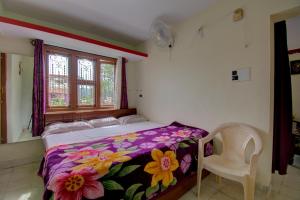 a bedroom with a bed and a chair and a window at Chuppi Homestay in Madikeri