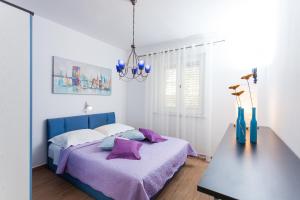 a bedroom with a bed with purple sheets and a table at Holiday Home Dada in Vela Luka
