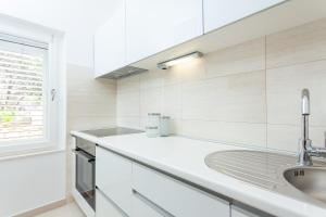 a white kitchen with a sink and a window at Holiday Home Dada in Vela Luka +20 photos