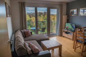 a living room with a couch and a balcony at Lochend Park View Apartment in Edinburgh