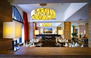 呂貝克的住宿－呂貝克H + 酒店，一间带桌椅和吊灯的餐厅