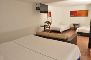 a room with two beds and a tv on the wall at Chrisban Hotel Boutique in Buga