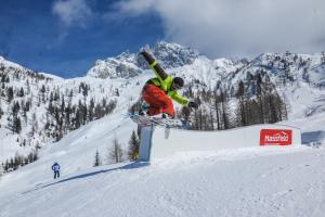a man riding a snowboard on a rail in the snow at Apartments Bergblick in Sonnenalpe Nassfeld