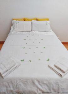 リスボンにあるApartamento Realの白いシーツと緑の蝶が乗ったベッド