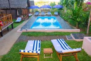 a pool with chairs and umbrellas in the grass at Bungalows des tropiques in Nosy Be