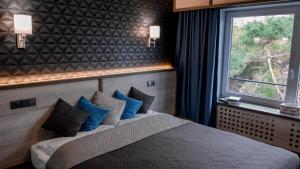 Bradlec的住宿－Exclusive Pension Vista Mlada Boleslav，一间卧室配有一张带蓝色枕头的床和一扇窗户。