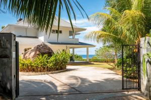 Pointe Au Sel 的住宿－Blue Horizon Villas，棕榈树和海洋房子的大门