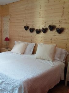 a bedroom with a bed with white pillows and a wooden wall at Hotel Pedretti in Branzi