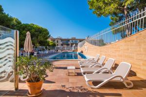 a row of lounge chairs next to a swimming pool at Hotel Baviera in Cala Ratjada