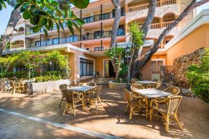 an outdoor patio with tables and chairs in front of a building at Hotel Baviera in Cala Ratjada