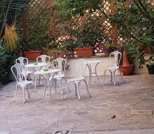 eine Gruppe von weißen Tischen und Stühlen auf einer Terrasse in der Unterkunft Daniela House 3 in Anzio