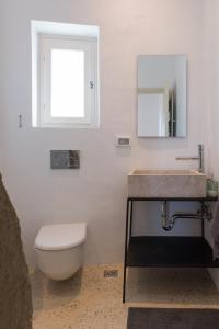 a bathroom with a sink and a toilet and a mirror at Katavati - 2 Semi-detached Houses in Apollonia