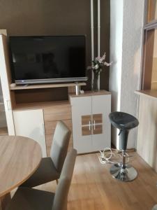 a living room with a television and a table and chairs at Apartman Centros in Osijek