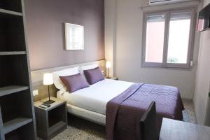 sypialnia z łóżkiem z fioletowymi poduszkami i oknem w obiekcie Hostal Fonda Montserrat w mieście Cambrils
