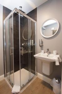 uma casa de banho com um chuveiro, um lavatório e um espelho. em The Rusty Mackerel em Teelin