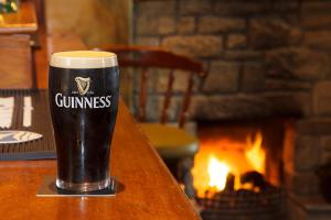 a glass of beer sitting on a table with a fireplace at The Rusty Mackerel in Teelin