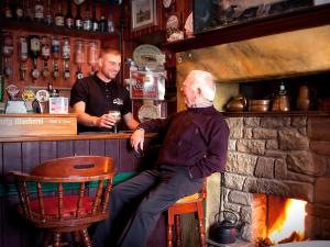 an older man sitting at a bar with a bartender at The Rusty Mackerel in Teelin