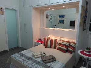 1 dormitorio con cama con almohadas y espejo en Charmoso Studio Ipanema, en Río de Janeiro