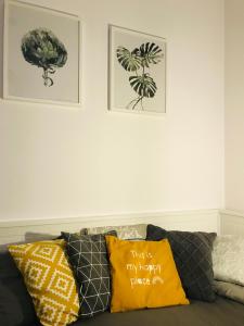 a couch with pillows and two pictures on the wall at Apt Pawia in Warsaw