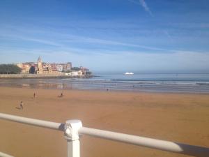 vistas a una playa con gente caminando por la arena en Apartamentos Plaza Mayor, en Gijón