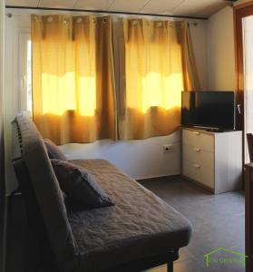a bedroom with a couch and a tv and curtains at CAL GENERAL in La Cellera de Ter