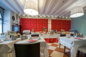 un restaurante con mesas blancas y cabinas rojas en Hotel Bologna ***S, en Verona