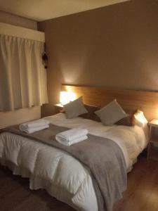 1 dormitorio con 1 cama blanca grande y 2 almohadas en Departamentos Patagonia en San Carlos de Bariloche
