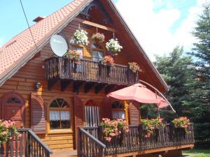 a house with flowers on the balconies and an umbrella at Kraina Szczęśliwości in Zawoja