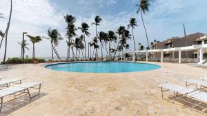 una piscina con sillas y palmeras en una playa en Crescent Cove 87 at Palmas, en Humacao