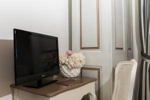einen Fernseher auf einem Tisch mit einer Blumenvase in der Unterkunft Tenuta D'Amore in San Mango Piemonte