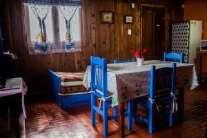 a dining room with a table and blue chairs at Cabaña El Metejon in El Bolsón