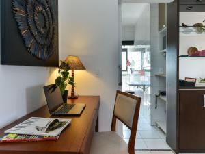 a desk with a laptop and a lamp on it at Apartamento Aconchegante com Vista Incrível, Piscina e Vaga in São Paulo