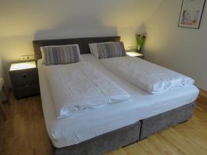 Hotel Saarblick Mettlach في ميتلاخ: سرير كبير عليه أغطية ووسائد بيضاء