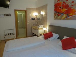 a bedroom with two beds and a bathroom with a sink at Hotel Saarblick Mettlach in Mettlach