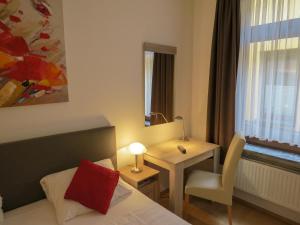 Hotel Saarblick Mettlach في ميتلاخ: غرفة فندقية بسرير وطاولة ونافذة