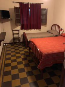 a bedroom with two beds and a checkered floor at Hotel Aguirre in Mina Clavero