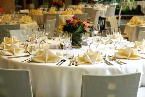 einen Tisch mit weißen Tischdecken, Servietten und Weingläsern in der Unterkunft Hotel Ajana in Ulcinj